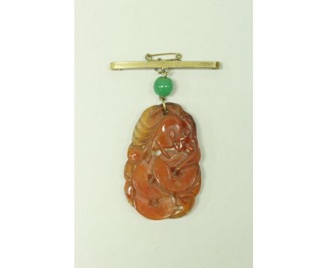 A Chinese carved hardstone pendant depicting a bat on circular discs, on suspension hook with green glass bead and bar brooch