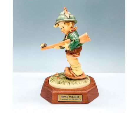 The figurine depicts a young soldier in uniform, standing proudly with his rifle in his hand. He is wearing a helmet and a ba