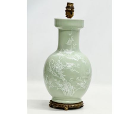 A Chinese Celadon glazed table lamp with brass base. Decorated with white prunus leaves and birds in flight. Early/Mid 20th C