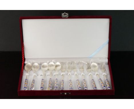 Cased set of champlevé white metal teaspoon and fork set, the matt white metal stamped 70 &amp; 99, red, blue and yellow enam