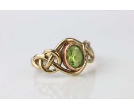 Peridot 9ct yellow gold ring, the oval mixed cut peridot measuring approx 6.5mm x 4.5mm, rub over set, openwork entwined shou