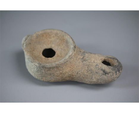 A Hellenistic period grey pottery oil lamp with a round body and long nozzle.   Ex, Baroness Ethel Inchiquin, Drromoland Cast
