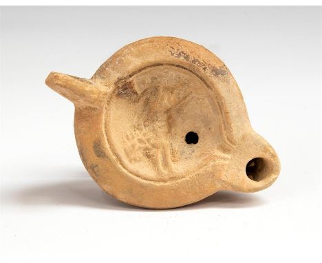 A terracotta oil lamp with projecting nozzle.   The oval body dished to the top and decorated with the figure of a running li