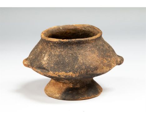 A ceramic vessel with wide mouth and rolled rim. Sloping shoulder with two small lug handles tothe carination.   The body slo