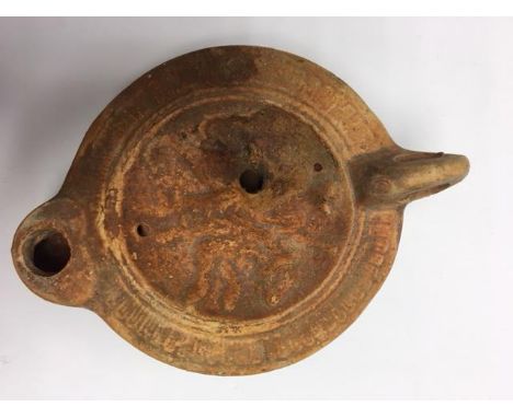 A Roman Terracotta oil lamp with heart shaped nozzle, oval body with series of ovules to the shoulder.   The dished centre de
