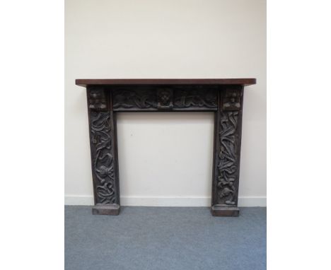 An 18th Century and later carved oak fire surround decorated with lions, leaves and husk, 115cm x 135cm