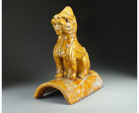 A Chinese sancai glazed roof tile, Qing Dynasty, of typical form and modelled as a seated lion dog, decorated with an amber c