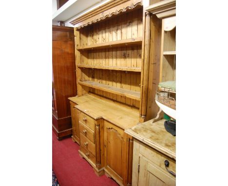 A reclaimed stained pine Victorian style kitchen dresser, having three-tier open plate rack over breakfront base, fitted with