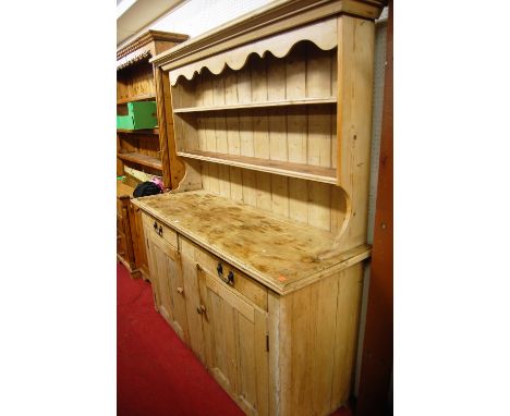 A Victorian pine kitchen dresser, the two-tier open plate rack with wavy frieze over base fitted with twin frieze drawers, to