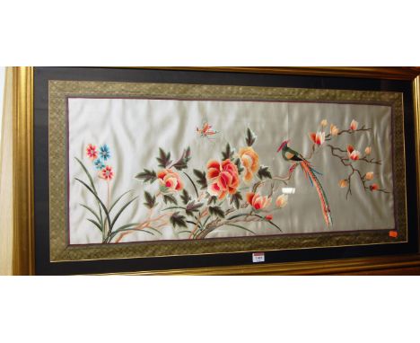 A modern Oriental silkwork panel depicting exotic bird and insect amidst blooming flowers, 38 x 87cm 