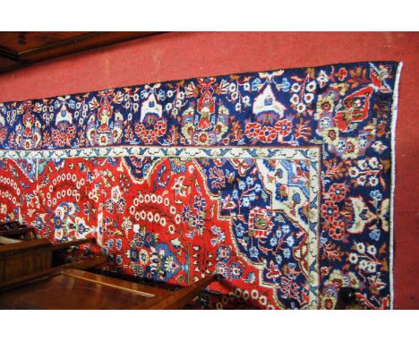 A Persian Mashad carpet having a red ground decorated with pedestal vases issuing flowers and foliage within a blue border, 2