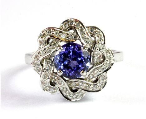A white metal (tested 14ct gold) flower shaped ring set with a brilliant cut tanzanite and diamonds, (Q).
