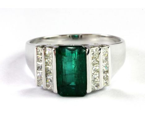 A 14ct white gold (stamped 585) ring set with an emerald cut emerald and diamonds, (P).