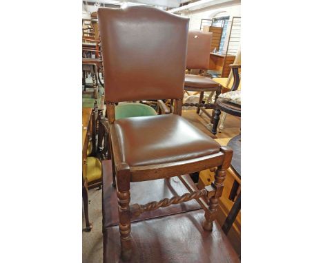 A set of eight oak framed panel back dining chairs with studded brown leather upholstery and drop-in seats, set on turned fro