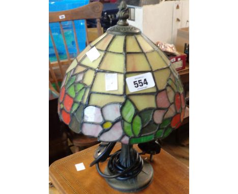 A cast metal table lamp with bronzed finish and Tiffany style stained glass shade