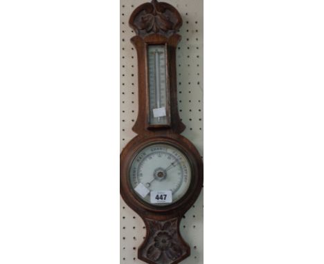 A late Victorian carved oak framed banjo barometer/thermometer with printed ceramic dial and aneroid works