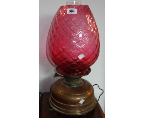 A brass oil lamp with large ribbed cranberry shade and clear glass chimney - converted to electricity