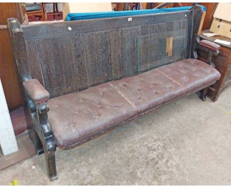 A 1.85m old stained oak panel back bench with flanking open armrests and original button back upholstered rexine seat, set on