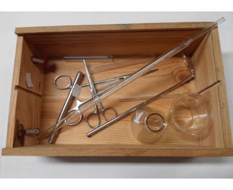 A wooden box containing assorted medical instruments including test tube, scissors, flask, etc.