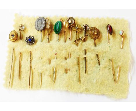 A cloth wrap containing a collection of yellow metal and other stick pins including opal, tourmaline, malachite and seed pear