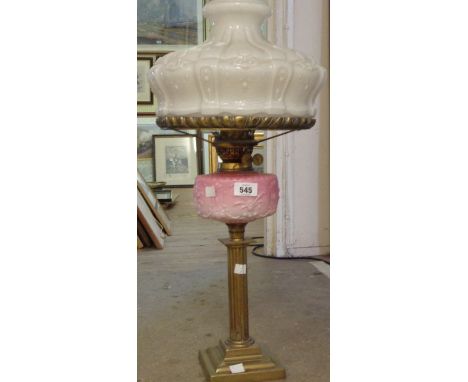 A Victorian oil lamp with brass Corinthian column stand and opaque pink glass reservoir with chimney and large opaque white g