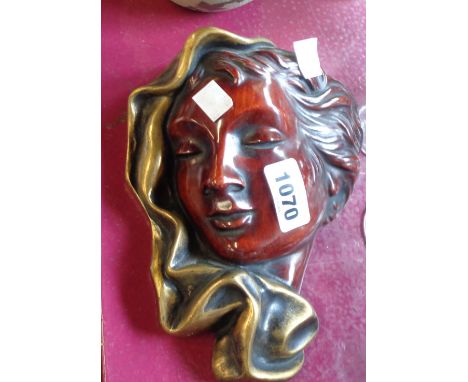 A modern German pottery wall mask in the Art Deco style depicting a lady with scarf, decorated with a faux wood glaze effect 