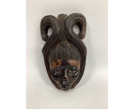 A 1950's Carved African Female Face Mask, wearing a scrolling headdress, 37cm long.