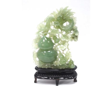 A Mid/Late XX Century Jadeite Carving of a Dragon Surmounting Gourds and Foliage, hardwood stand, 32cm high.