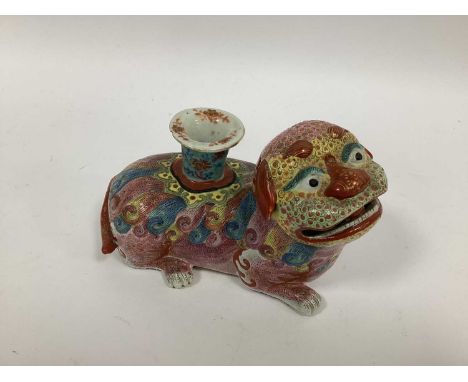 An Early XX Century Japanese Pottery Candle Holder, modelled as a colourfully decorated recumbent Dog of Fo, the candle sconc