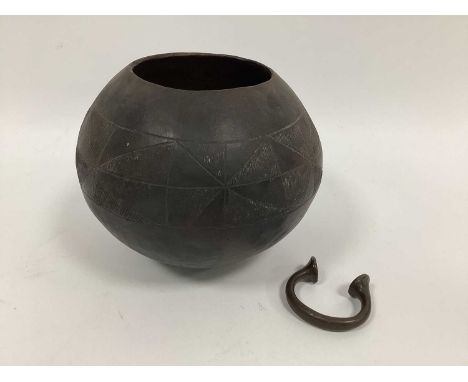 An African Zulu Clay Globular Beer Pot, incised with a band of geometric motifs, 16cm high and a Manilla Slave Bracelet. (2)