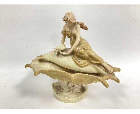 A Royal Dux Pottery Model of a Lady Seated on a Shell, feeding a bird, pink triangle mark, shape number, 1931, 28cm high.some