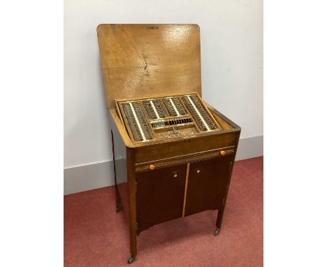 A 1930's Oak Cased Wheeled Cabinet of Optician's Lenses, with lift-up top, sliding shelf and two doors to the lower section; 