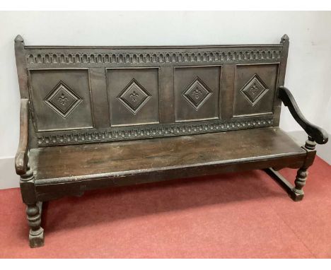 A XVII Century and Late Joined Oak Settle, the top rail with knulled decoration, four lozenge panels to back, seat, shaped ar