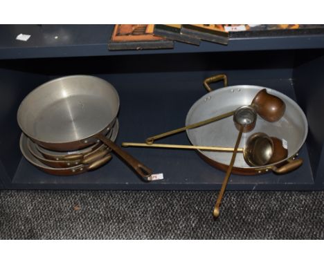 An assorted collection of vintage copper and stainless steel graduating and other pans, plus ladles