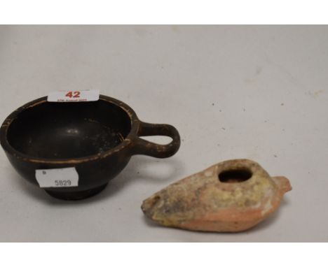 An earthenware oil lamp, measuring 10cm long, &amp; a Greek style ebonised cup with ring handle