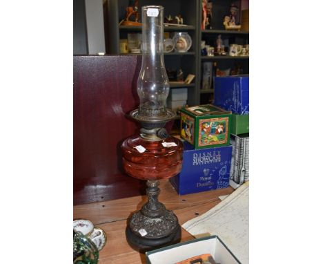A late 19th Century oil lamp, having a cranberry glass reservoir and a pierced cast metal base, measuring 64cm tallCondition 