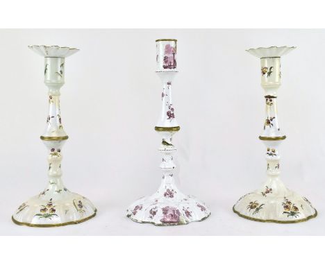 A pair of mid 18th century c1765 Bilston enamel candlesticks, along with one other. The pair with petal sconces, decorated wi