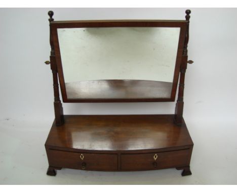 An early 19th Century mahogany swing toilet mirror, the rectangular framed plate on ring turned supports above a bowfront box