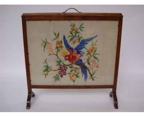 An Edwardian mahogany framed fire screen inset with a silk tapestry panel depicting a parrot on a fruiting branch. 