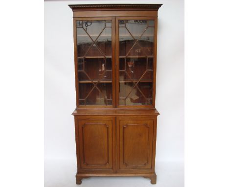 A late 19th Century George III style mahogany bookcase cabinet, the dentil cornice above a plain frieze and a pair of astraga