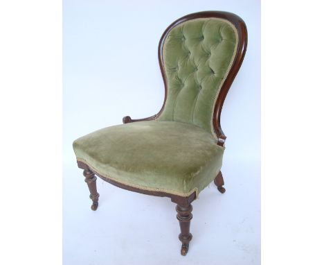 A Victorian walnut framed spoon back nursing chair, with buttonback upholstery on turned forelegs with ceramic casters. 