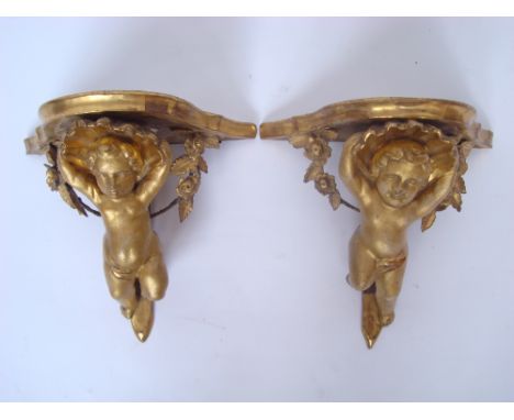 A pair of 19th Century Continental carved giltwood and gesso wall brackets, each with a serpentine shelf supported by a putto