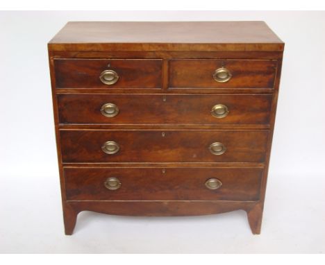 An early 19th Century mahogany chest of drawers, with two short and three graduated long cockbeaded drawers with later oval b