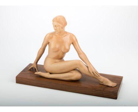 Ian Norbury (living) A carved limewood nude, seated with legs crossed on a walnut plinth, 29 x 42.5 x 15.5cm (total), togethe