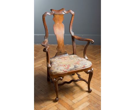 An early 18th century possibly Irish provincial walnut spoon back open armchair, raised on bifurcated cabriole forelegs and k