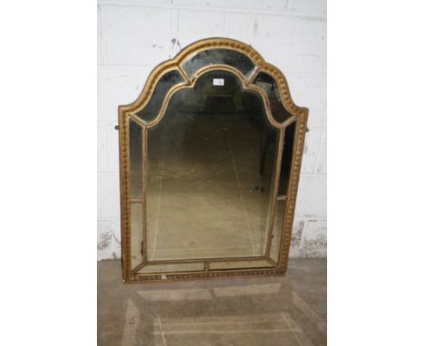 A 19th century giltwood and gesso wall mirror, the arched downswept rectangular frame with beaded and leaf slip enclosing a b