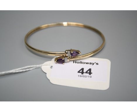 An Amethyst and diamond bangle, the polished yellow metal band with pear shaped amethyst and two stone diamond terminals