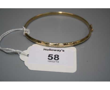 An engraved 9ct gold bangle with push button clasp