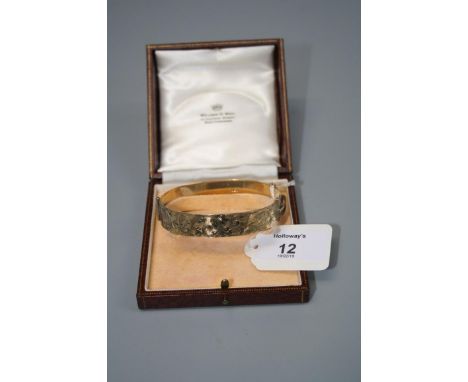 A 9ct gold bangle, scroll engraved decoration, push button clasp in fitted case