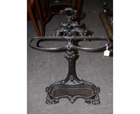 A Victorian style cast iron two division stick stand with serpentine drip tray on florally moulded feet